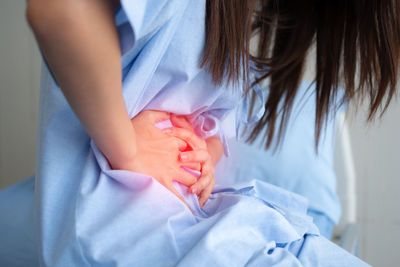 Midsection of woman holding hands on bed