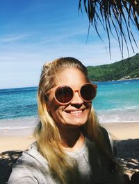 Close-up of woman wearing sunglasses at beach against sky