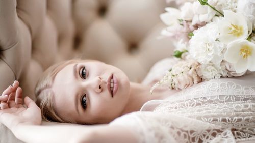 Portrait of woman with flowers lying on sofa