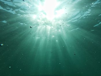 Low angle view of sunbeam streaming in sea