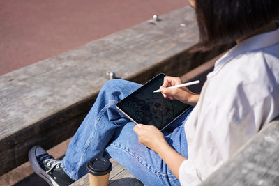 Low section of woman using mobile phone