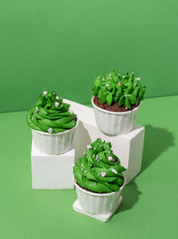 Green christmas tree shaped cupcakes on white poduims, abstract and modern minimal style