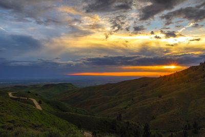 Scenic view of landscape against dramatic sky during sunset