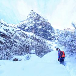 Rear view of people on snowcapped mountain against sky