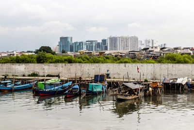 Boats moored in river against buildings in city