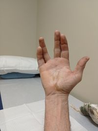 Close-up of person hand on bed against wall