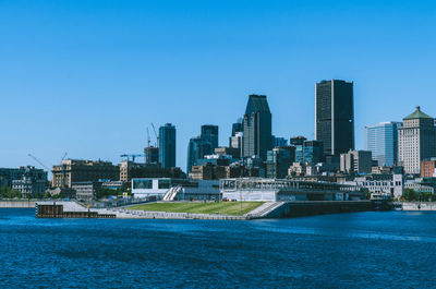 Sea by buildings against clear blue sky