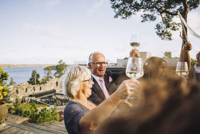 Happy friends enjoying and toasting wineglasses during wedding celebration