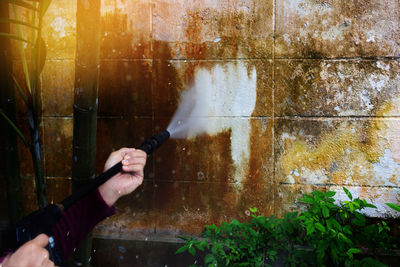 Cropped hands cleaning weathered wall