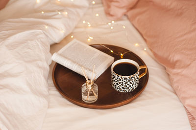 High angle view of coffee on tray with book and diffuser 