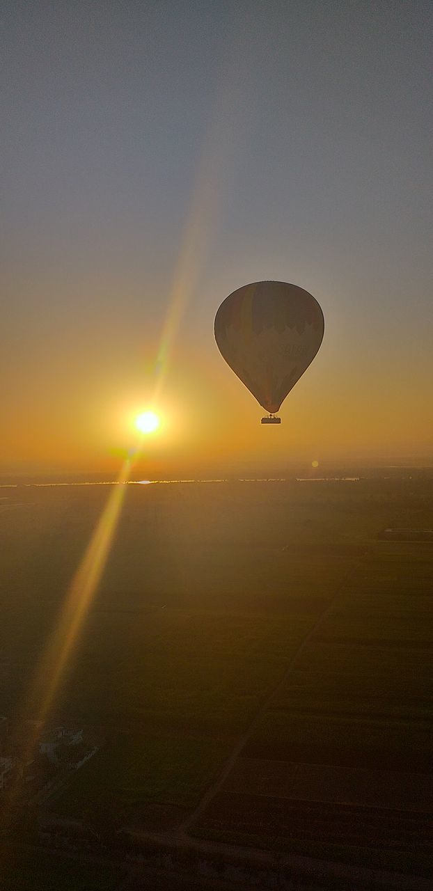 sky, sunset, sun, transportation, air vehicle, sunlight, mid-air, sunbeam, landscape, scenics - nature, environment, nature, beauty in nature, flying, mode of transportation, hot air balloon, lens flare, balloon, adventure, orange color, no people, outdoors, bright, brightly lit