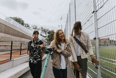 Happy teenagers walking together with scooter