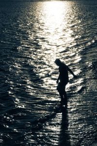 Silhouette of people in water at sunset