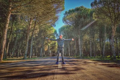 Man standing on road by trees in forest