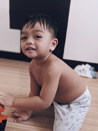 Cute boy looking away while relaxing on floor at home