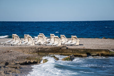 Empty beach chairs and closed sun umbrellas on the beach in greece.