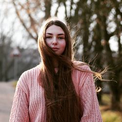 Portrait of beautiful young woman against trees