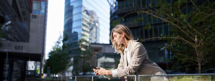 Side view of young woman standing in city