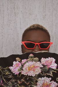 Close-up of woman wearing sunglasses against wall