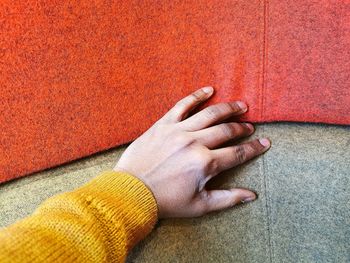 Close-up of hand touching orange wall