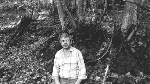 Man posing sitting in forest with an old shirt on resting.