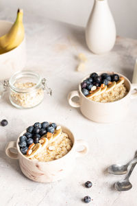 Close up of bowls with oatmeal porridge with blueberries for breakfast