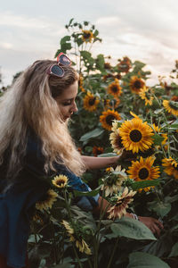 Portrait of young woman with sunflower amidst plants