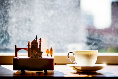 Coffee cup and centerpiece on table against window