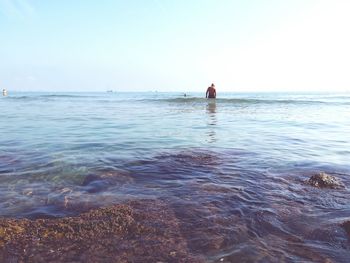 Rear view of man in sea against clear sky