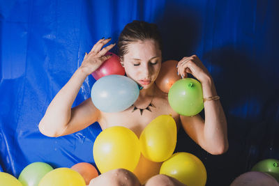 Shirtless woman with colorful balloons at home