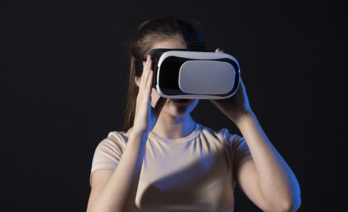 Portrait of young woman photographing against black background