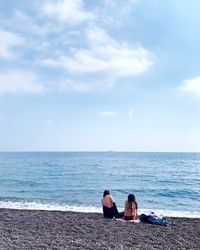 Rear view of women on beach against sky