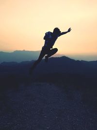 Silhouette man jumping against sky during sunset