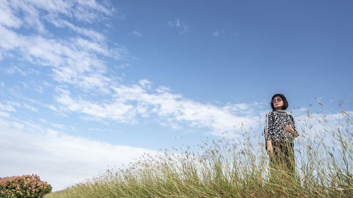 Side view of woman standing on field against sky