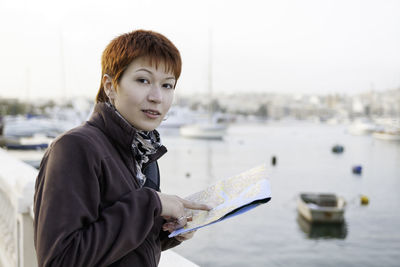 Woman with short red haircut reads malta map. curious woman stands near msida yacht marina. malta.