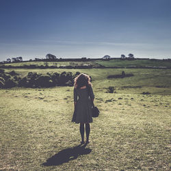 Rear view of woman standing on field against clear sky