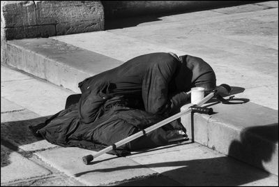 Beggar lying down on steps