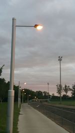 Illuminated street light against cloudy sky