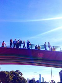 Low angle view of people against blue sky