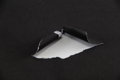 High angle view of cigarette on paper against black background