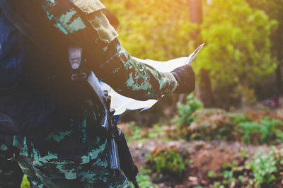 Midsection of soldier holding map on field