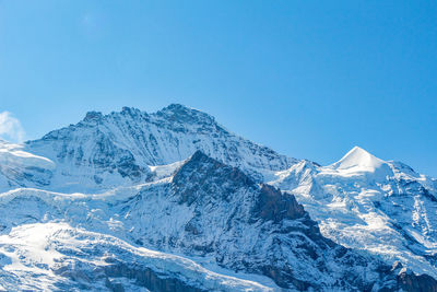 Scenic view of snowcapped mountains against clear blue sky