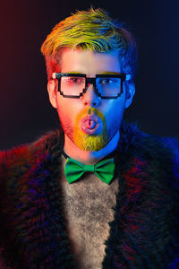 Portrait of man sticking out tongue against black background