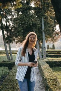 Happy young woman standing against tree