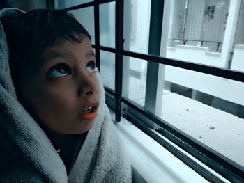 Portrait of boy looking through window