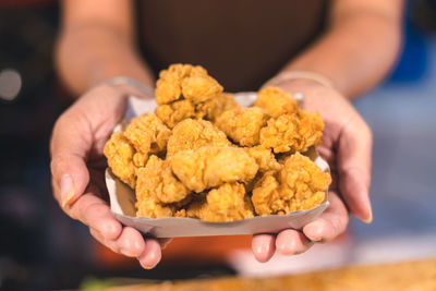 Midsection of person holding fried food in box