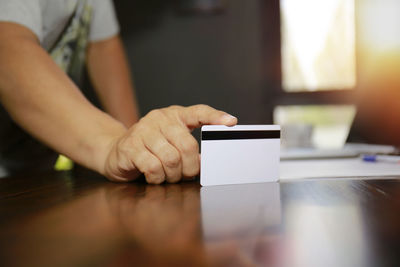 Midsection of man using mobile phone on table
