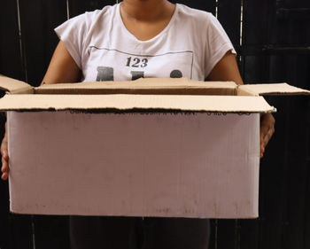 Midsection of man holding paper while standing at home