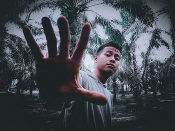 Portrait of young man standing by tree