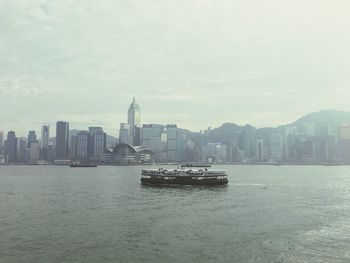 Boat sailing in river with city in background